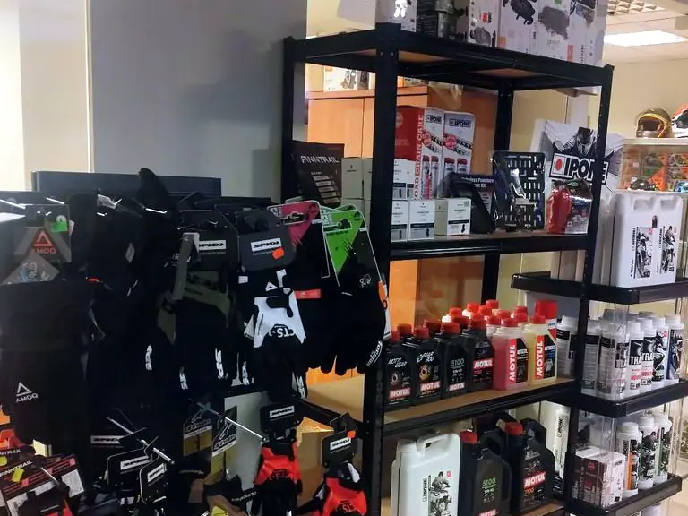 Pirštinių stovas ir lentynos su Motul bei Ipone alyvomis ir grandinių priežiūros priemonėmis